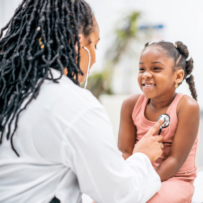 A doctor examining a young girl, representing when to call the pediatrician