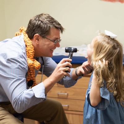 Pediatrician dr. Bryan mcdonlad examining a child, representing how pediatricians help children with chronic conditions