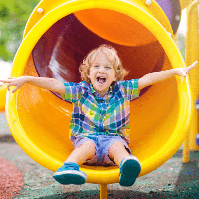 Child joyfully sliding down playground tube, representing healthy habits for kids
